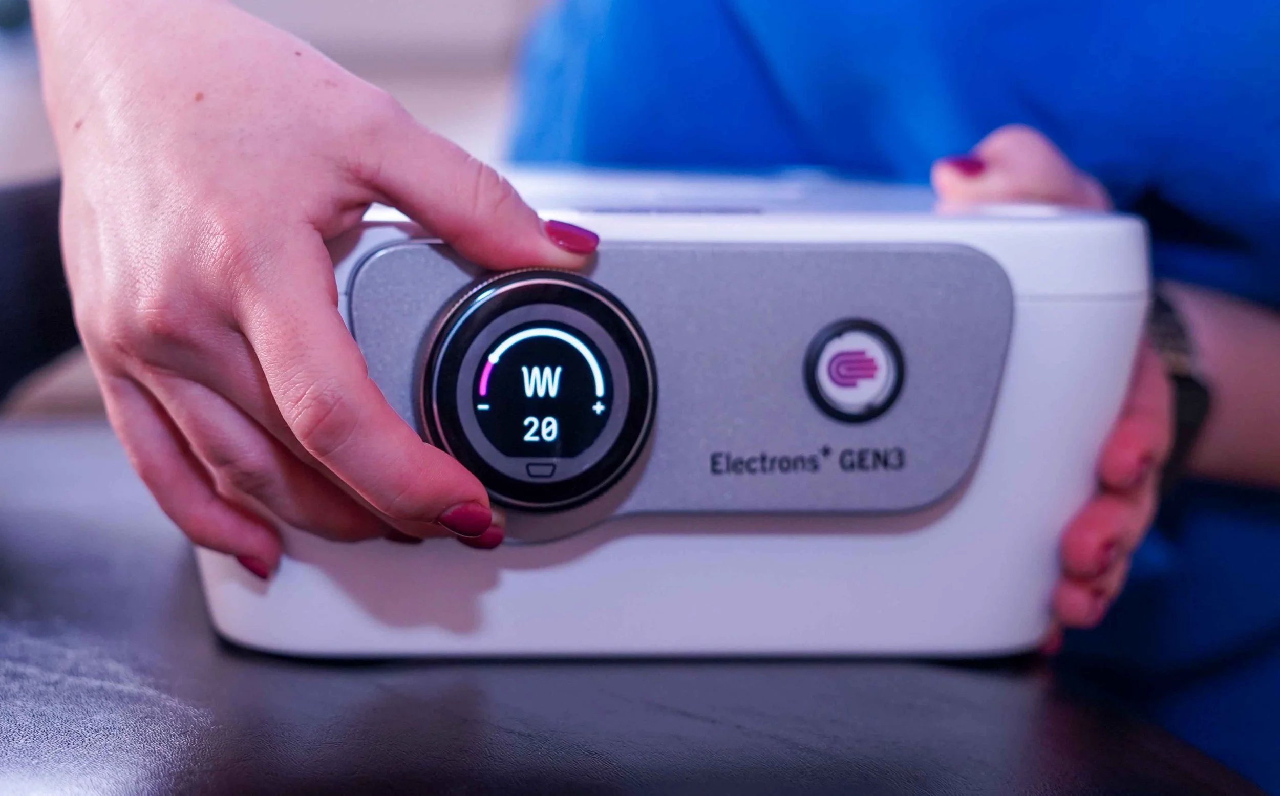 A practitioner holding the Electrons Plus GEN3 device, set to 20 watts